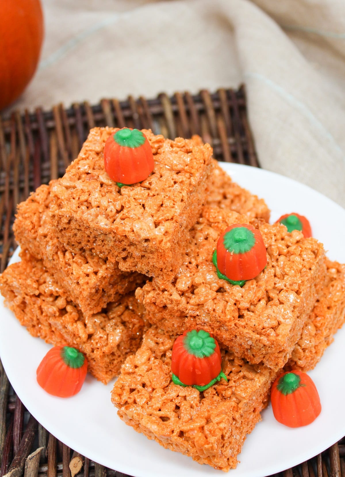 orange rice krispie treats cut into squares and stacked. Topped with a candy pumpkin.