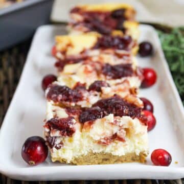 Cut bars of vanilla cheesecak2 with a cranberry swirl on a plate.