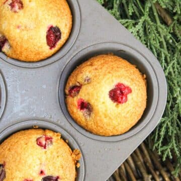 muffins in a muffin tin. Golden brown and topped with fresh cranberries.