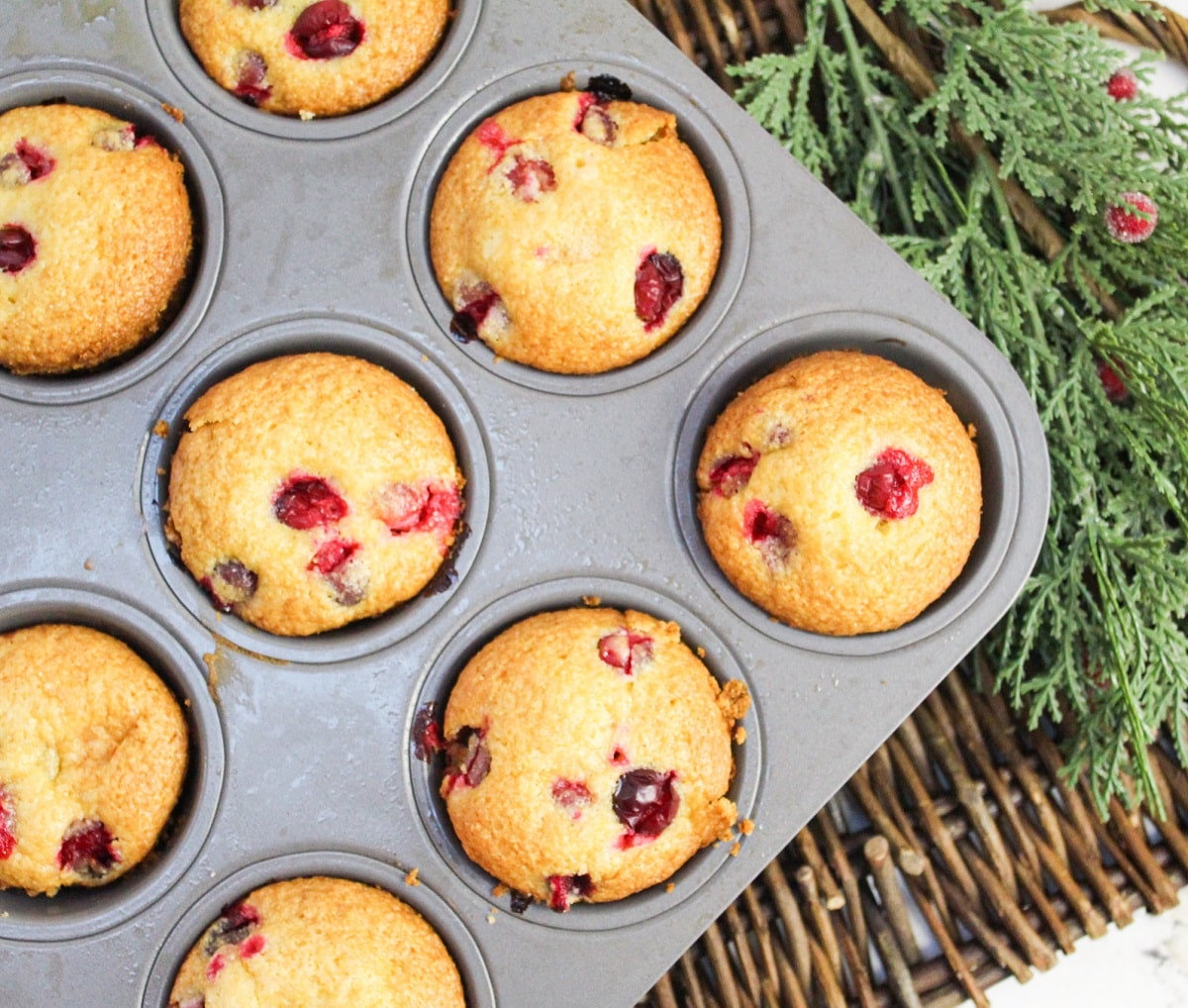 12 muffins in a muffin tin. Golden brown and topped with fresh cranberries.