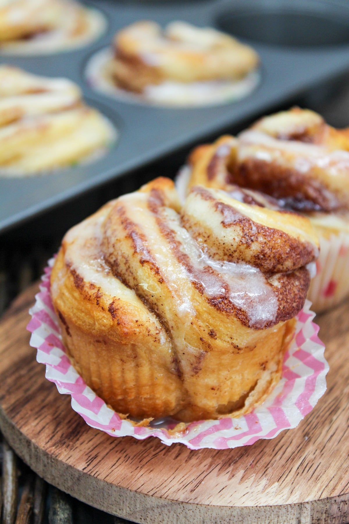 individual cinnamon rolls on a wooden board with a glaze on top.
