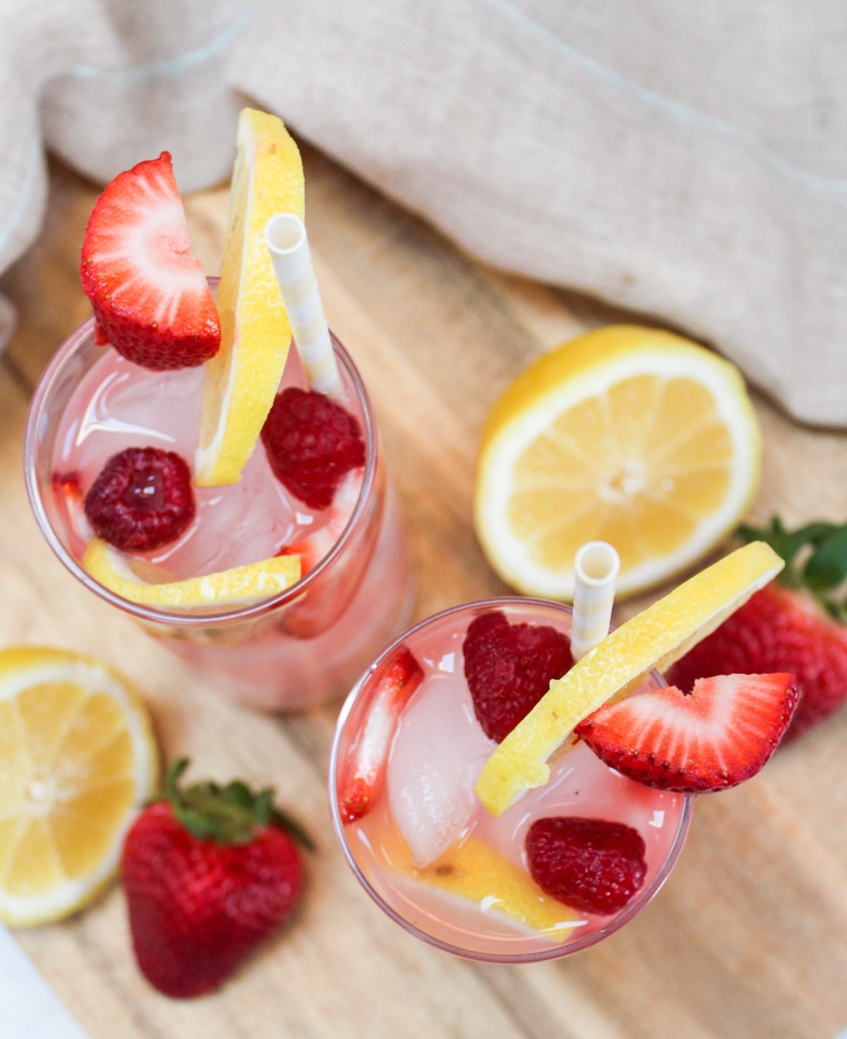 pink lemonade sangria in a tall glass garnished with strawberries, raspberries, and lemons.