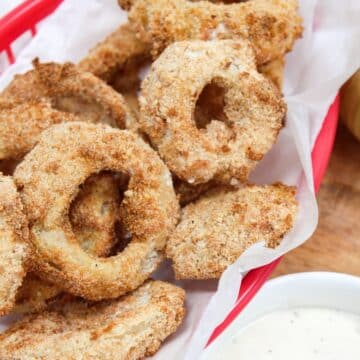 cooked onion rings in a red basket.