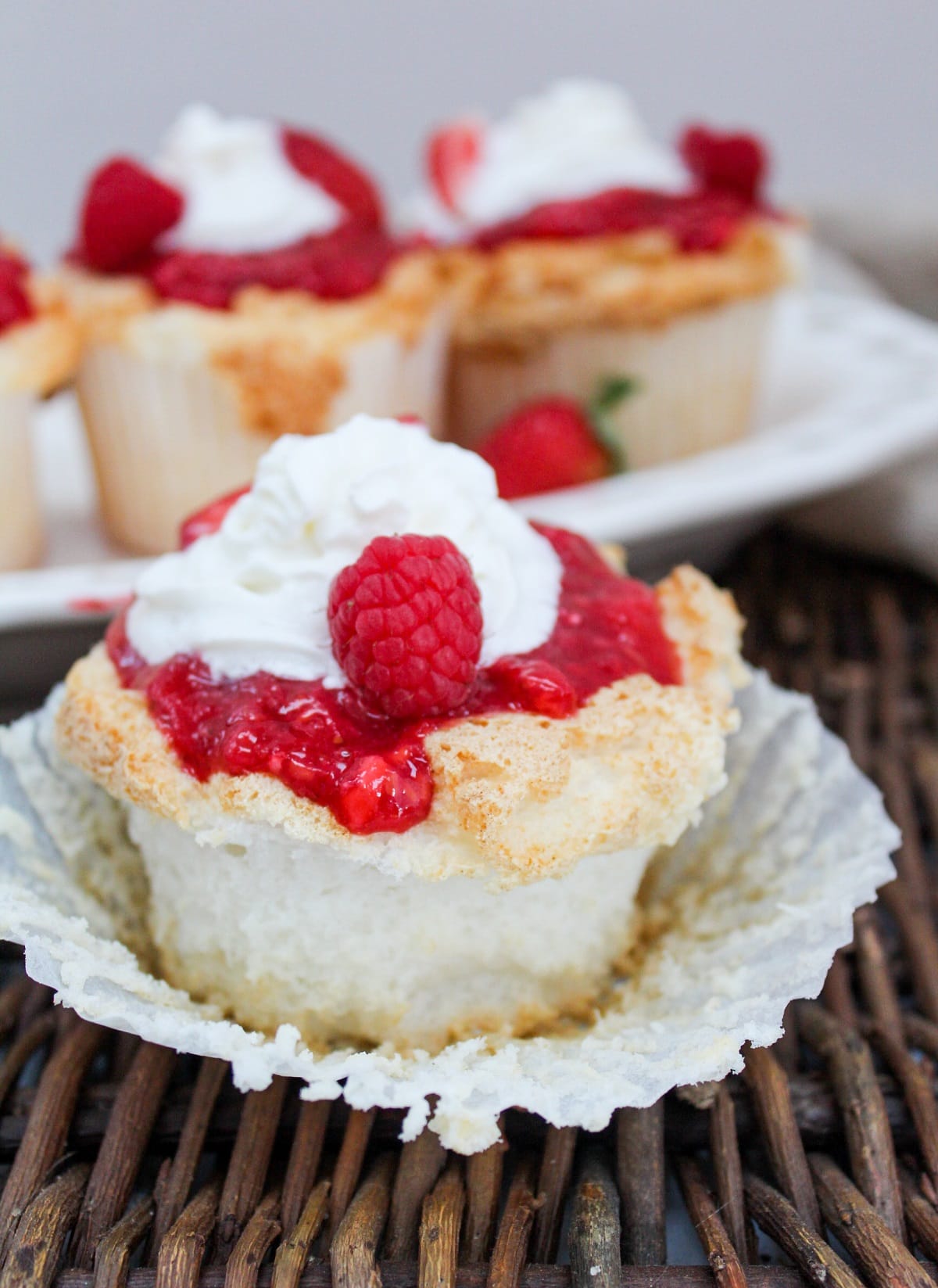 unwraped cupcake with berries and whipped cream on top.