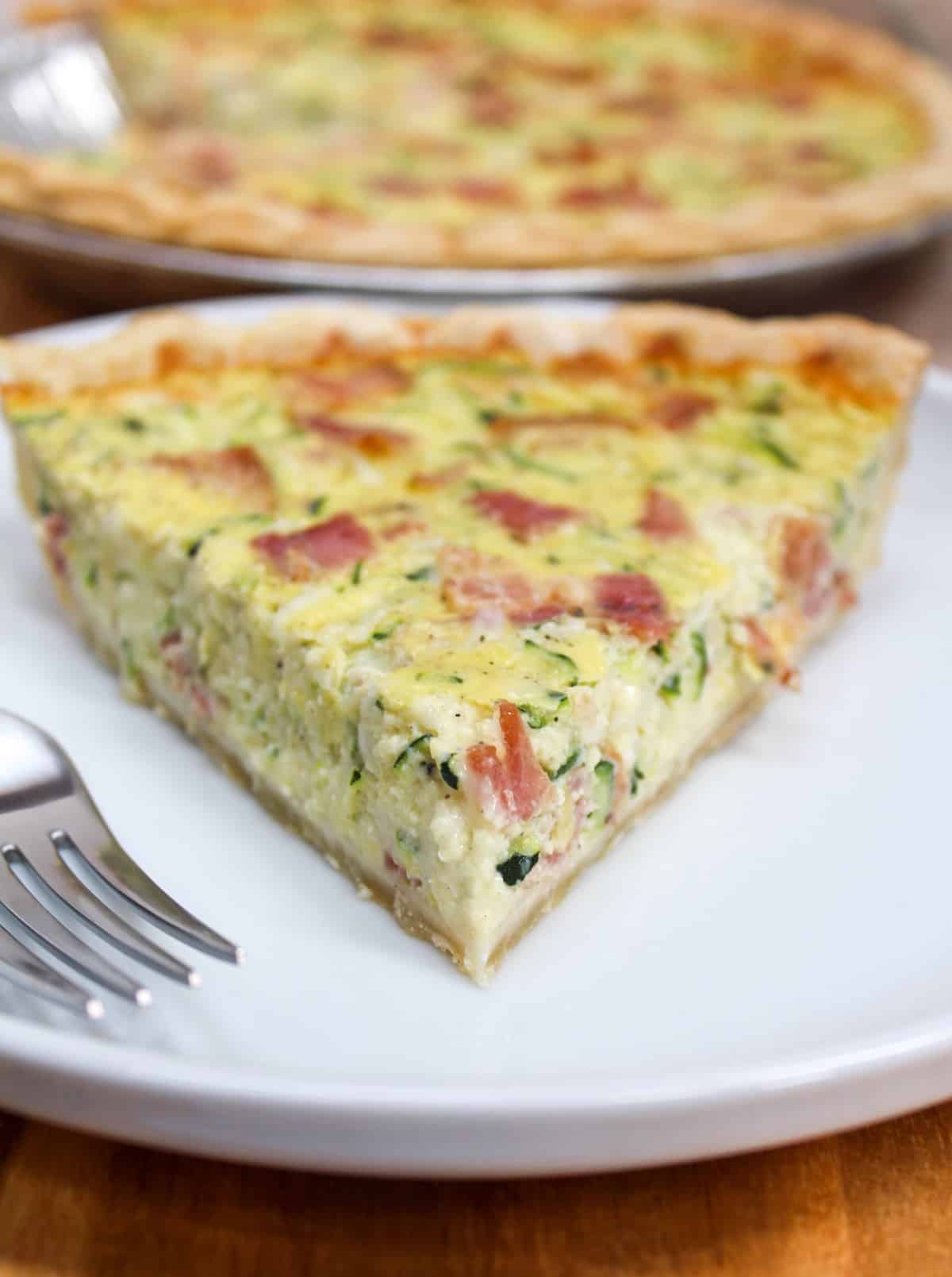 Sliced quiche on a white plate with a fork on the side.