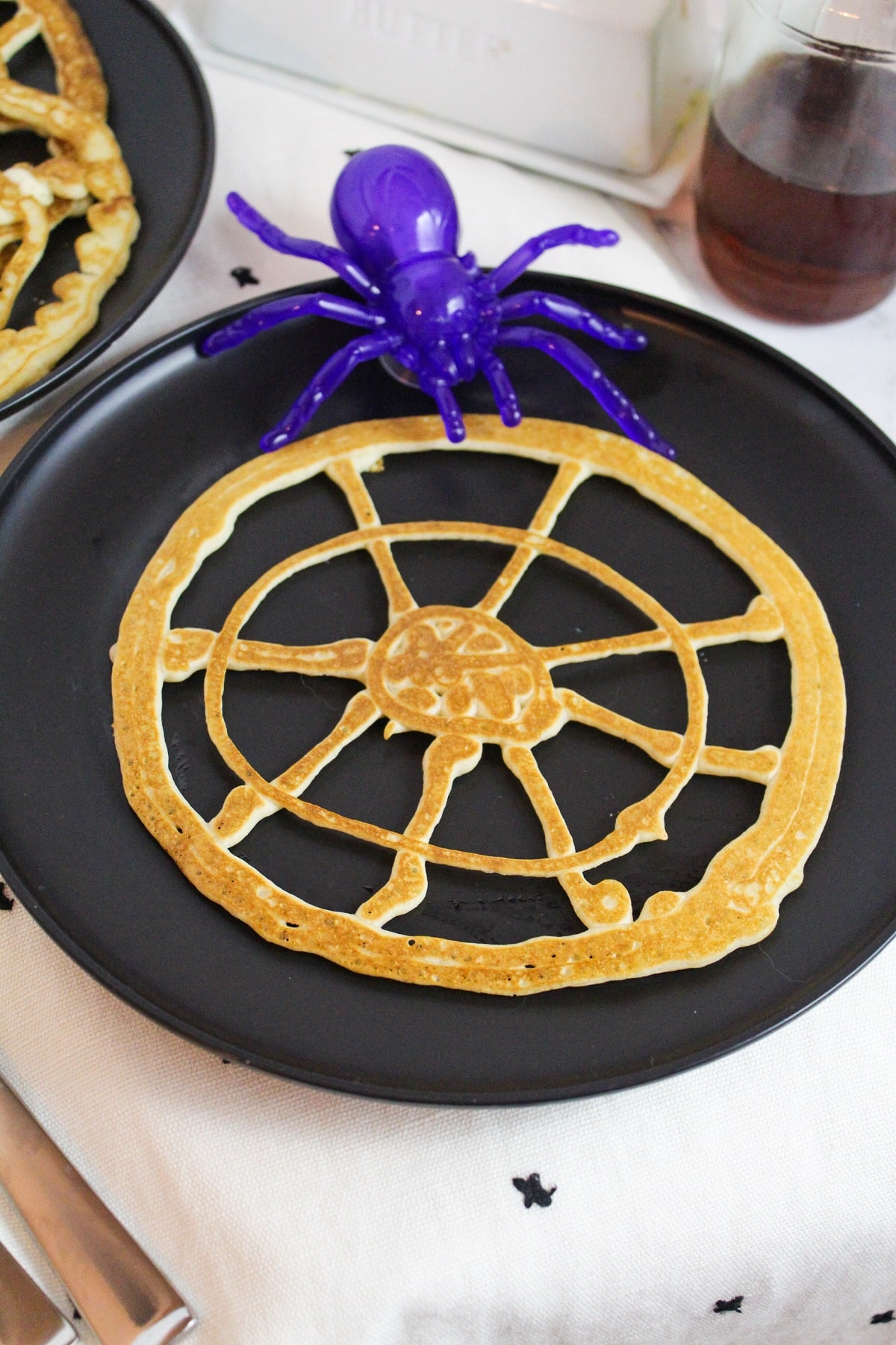 pancakes shaped like a round spider web with a plastic purple spider on the side.