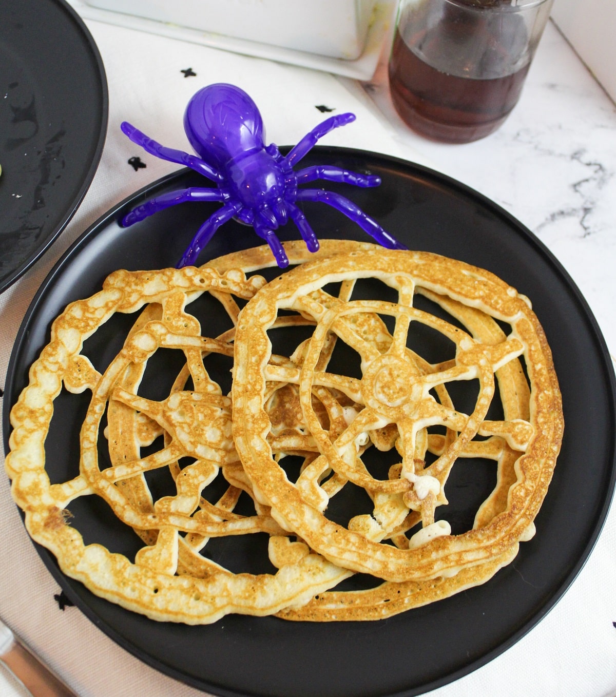 pancakes shaped like a round spider web with a plastic purple spider on the side.
